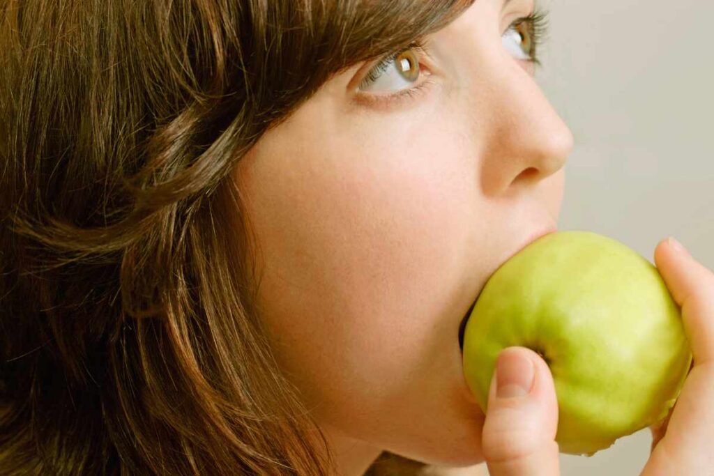 woman eating an apple for grinding teeth home remedies