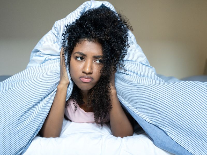 Girl under the covers having trouble with her sleep disorder